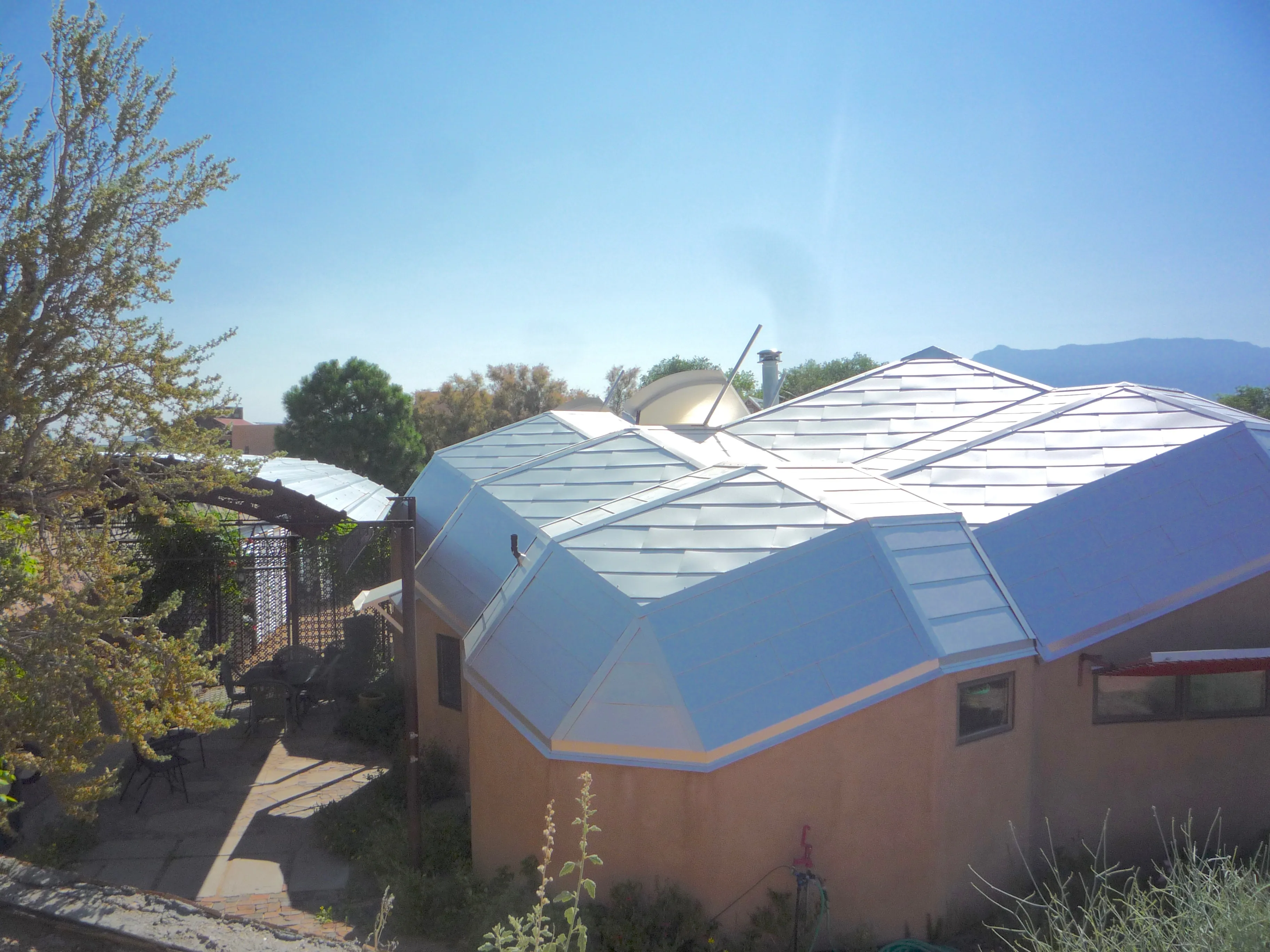 Aerial view of the zome house geodesic roof with triangular aluminum panels, Sandia Mountains in background
