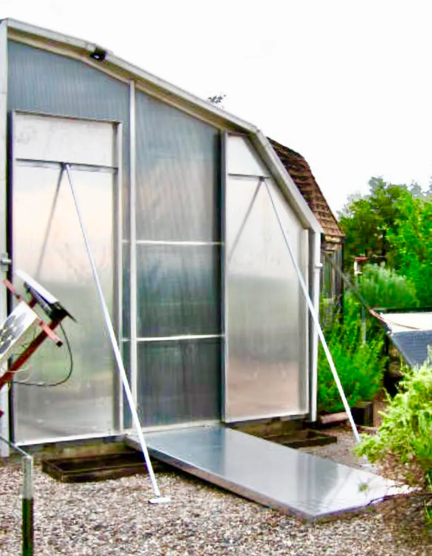Zomeworks shade and reflector system on south-facing outbuilding, with glazing panels and horizontal aluminum reflector deployed