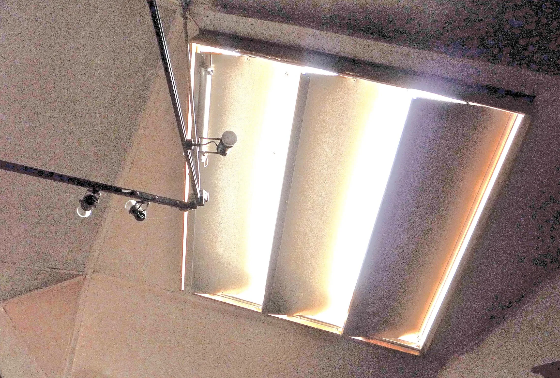 Looking up at open Skylid insulated louvers admitting sunlight through a ceiling skylight opening