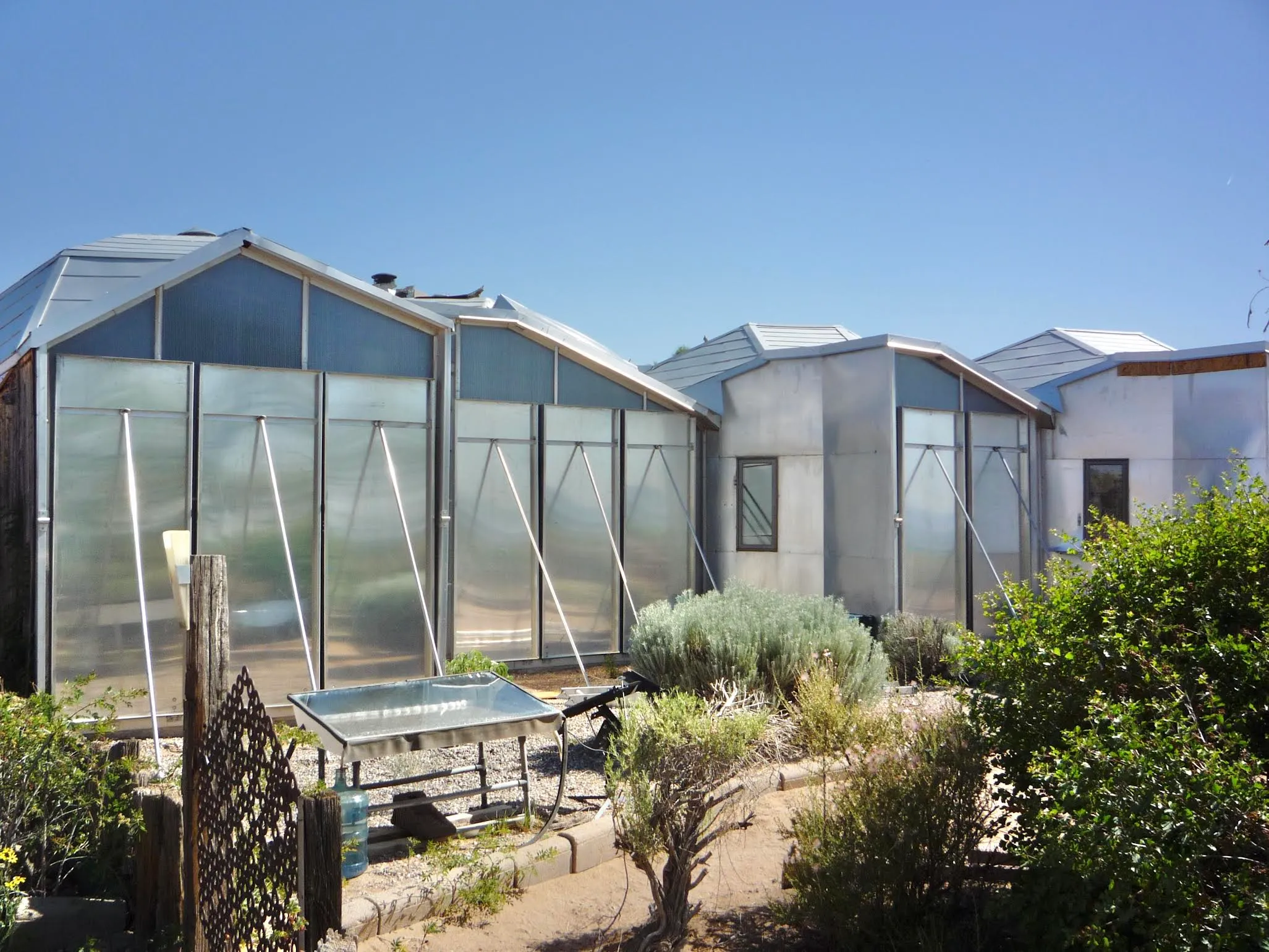 South-facing view of Zomeworks structure with large polycarbonate glazing panels propped open with aluminum support rods